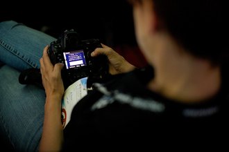 Someone is looking through a small monitor on their camera, which displays a white and blue settings menu.