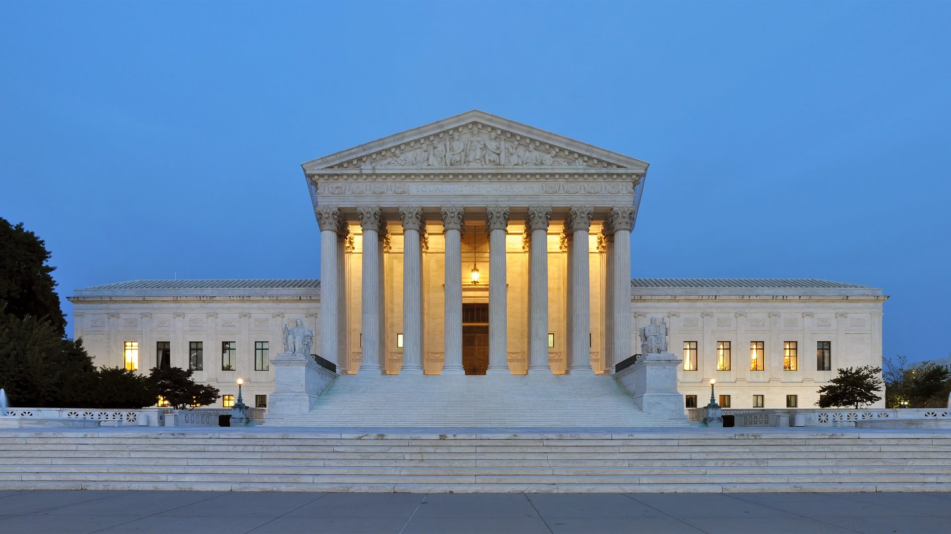 The Supreme Court building at dusk, before a clear blue sky