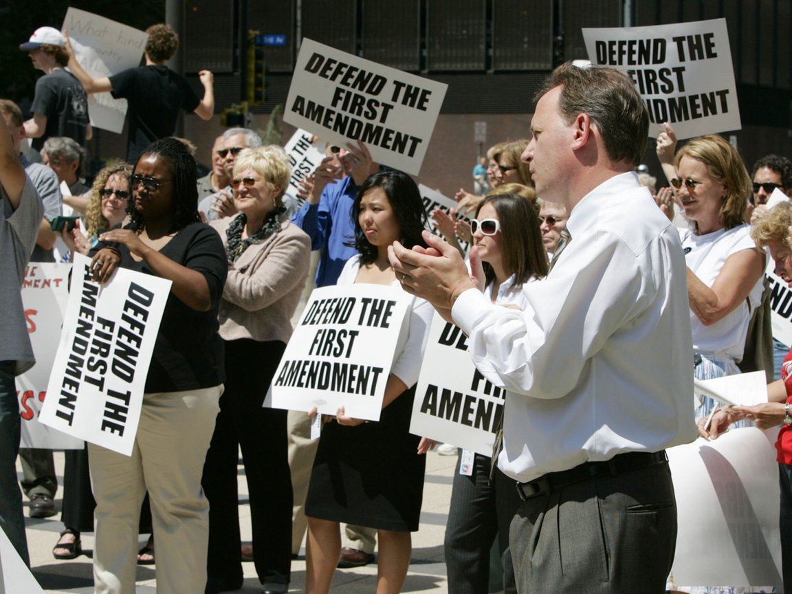 People holding "Defend the First Amendment" signs, photo by Jim Mone
