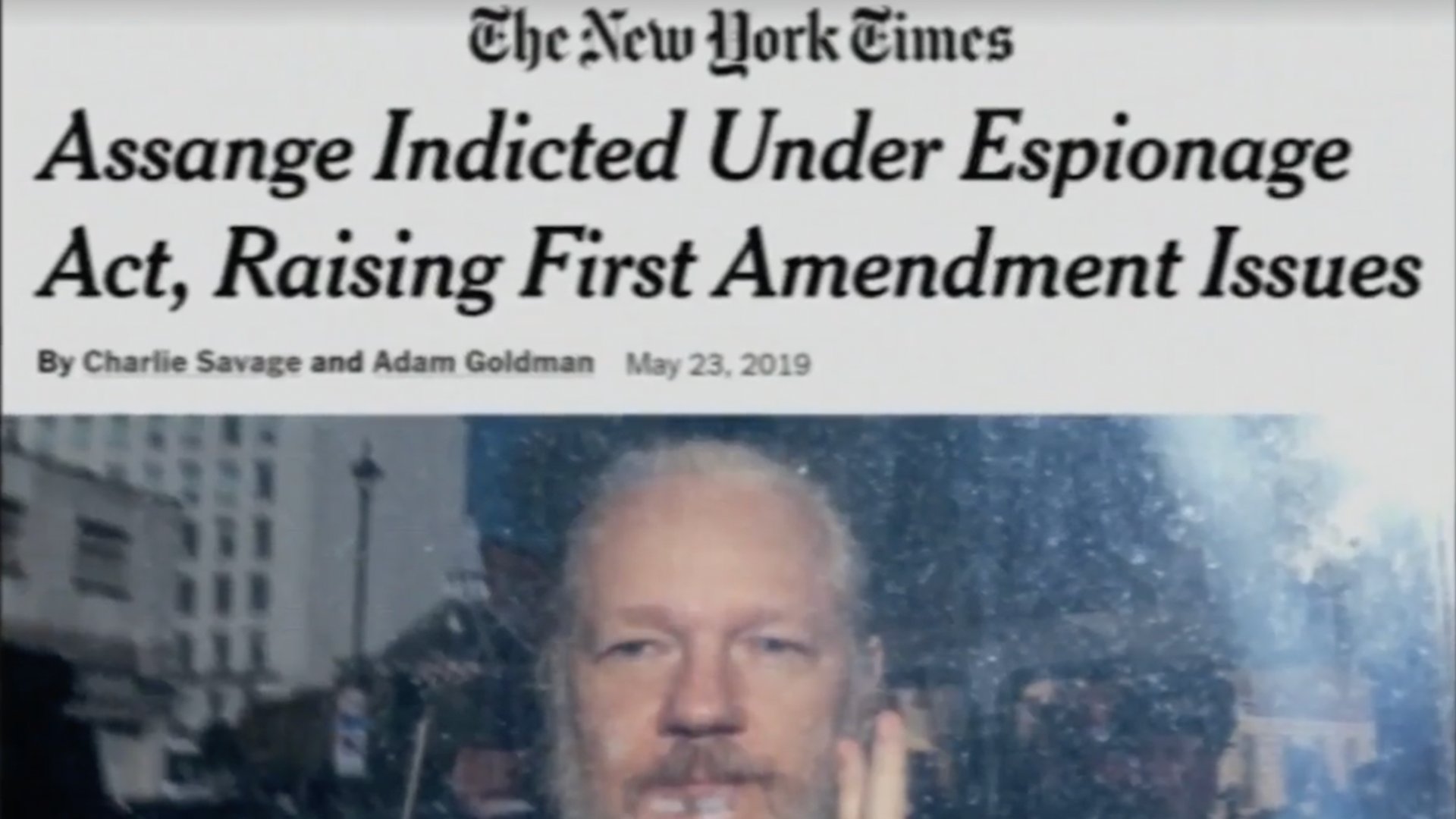 A New York Times headline, "Assange Indicted Under Espionage Act, Raising First Amendment Issues" appears over a picture of a bearded Julian Assange holding up two fingers.