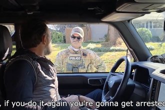 A masked federal agent tells a reporter he'll be arrested if he keeps reporting.