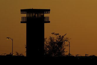 A prison watchtower against an orange sky.