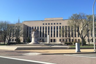 E. Barrett Prettyman U.S. Courthouse: A brown government building with a circle of figures carved in marble in front