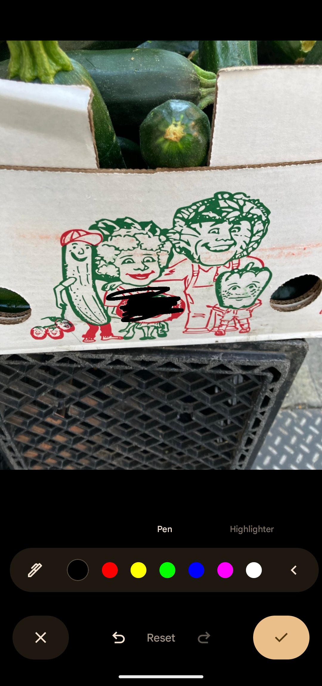 A screenshot of Android's Photos app showing a thick pen scribbling drawn over a face in an illustration of anthropomorphized vegetables on the side of a produce box.