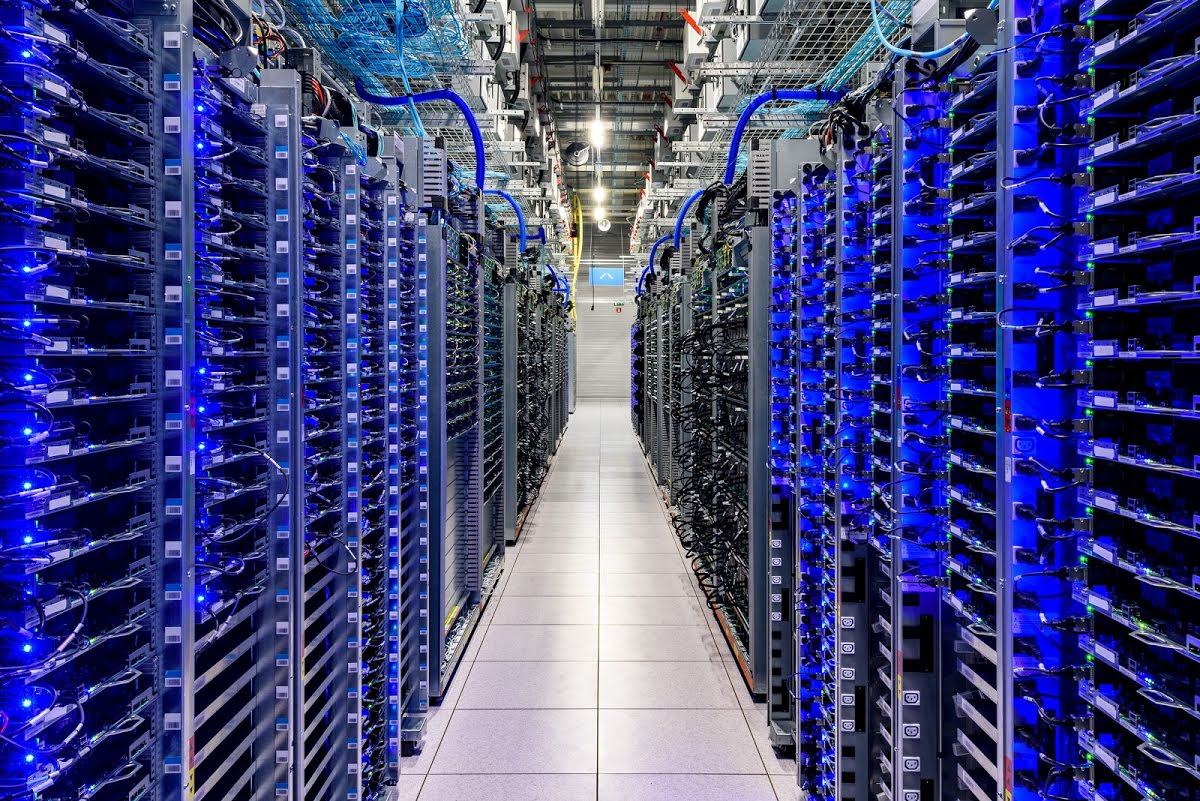 Rows of server racks, glowing blue inside of a Google data center.
