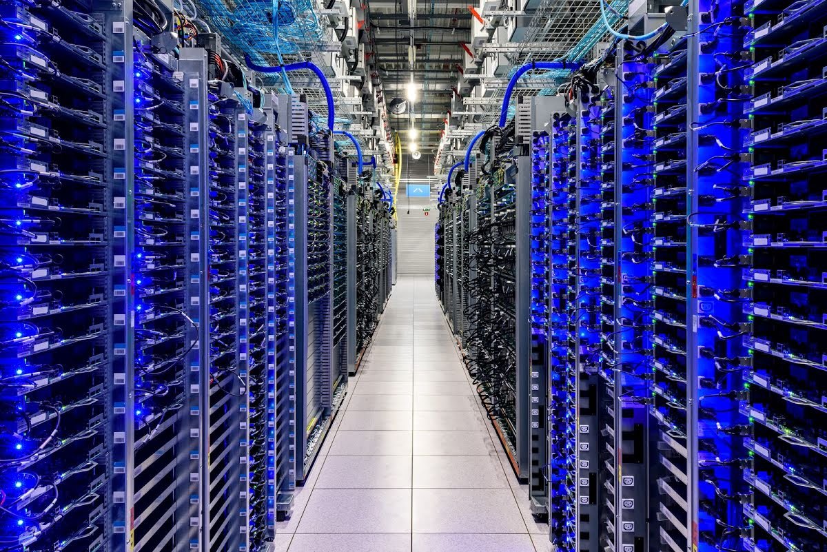 Rows of server racks, glowing blue inside of a Google data center.
