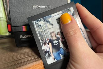 Header image of a Polaroid photo of the author, featuring a wide smile, with a Polaroid instant camera in the background.