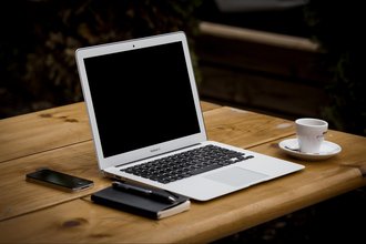 Image of a laptop with notebook, phone, and espresso on a table