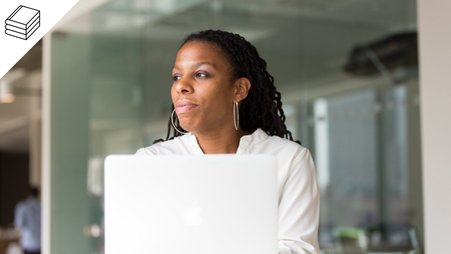 Header image of a woman sitting in front of her computer in an office.