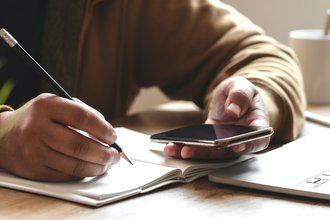 Cover image of a person holding a smartphone while writing
