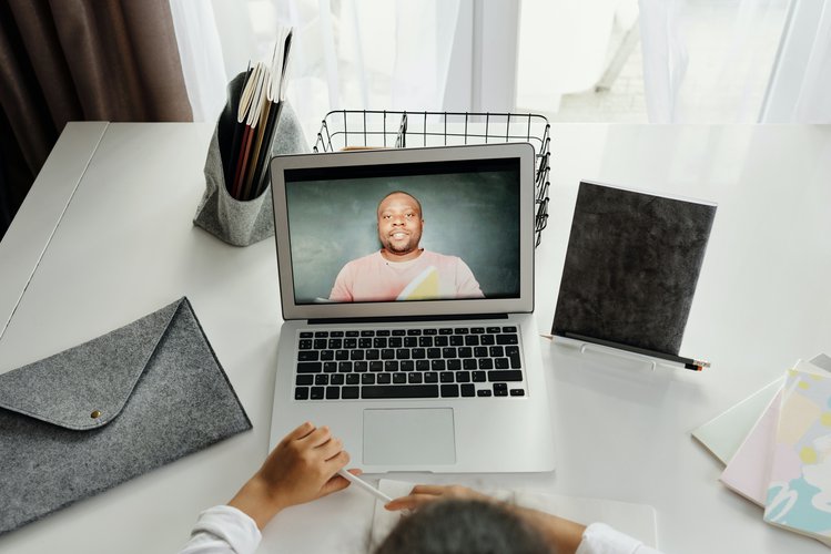 An image of a girl on a video call on her laptop. The screen displays an imgae of the person she's speaking to.