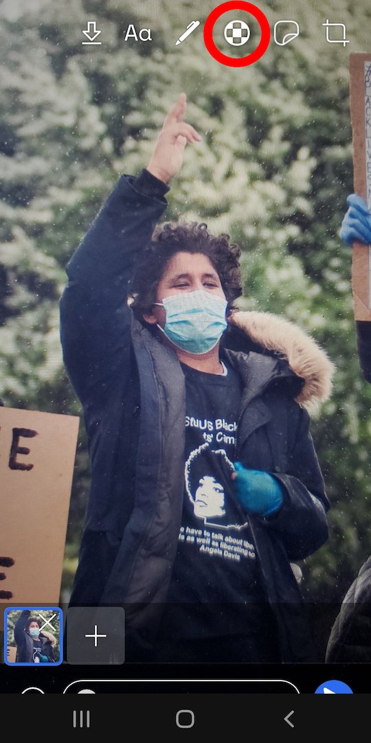 Screenshot of the photo interface within Signal, displaying a line of icons at the top of the screen, including the icon that leads to the face blurring interface. The photo features a masked protester pointing upward.