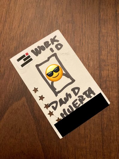 Example of an redacted work ID card which is actually a sharpie illustration it has a sunglasses face emoji over the face and black rectangle over the ID number