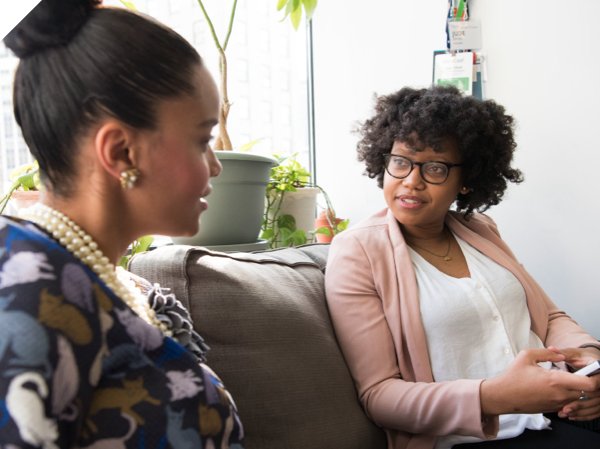 Header image of two women speaking to each other on a couch